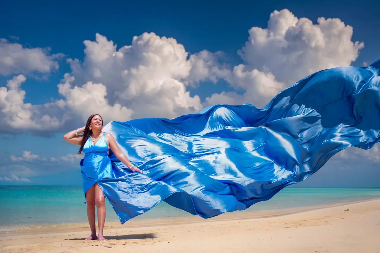 Guest posing in a flowing blue dress on a Jamaican beach