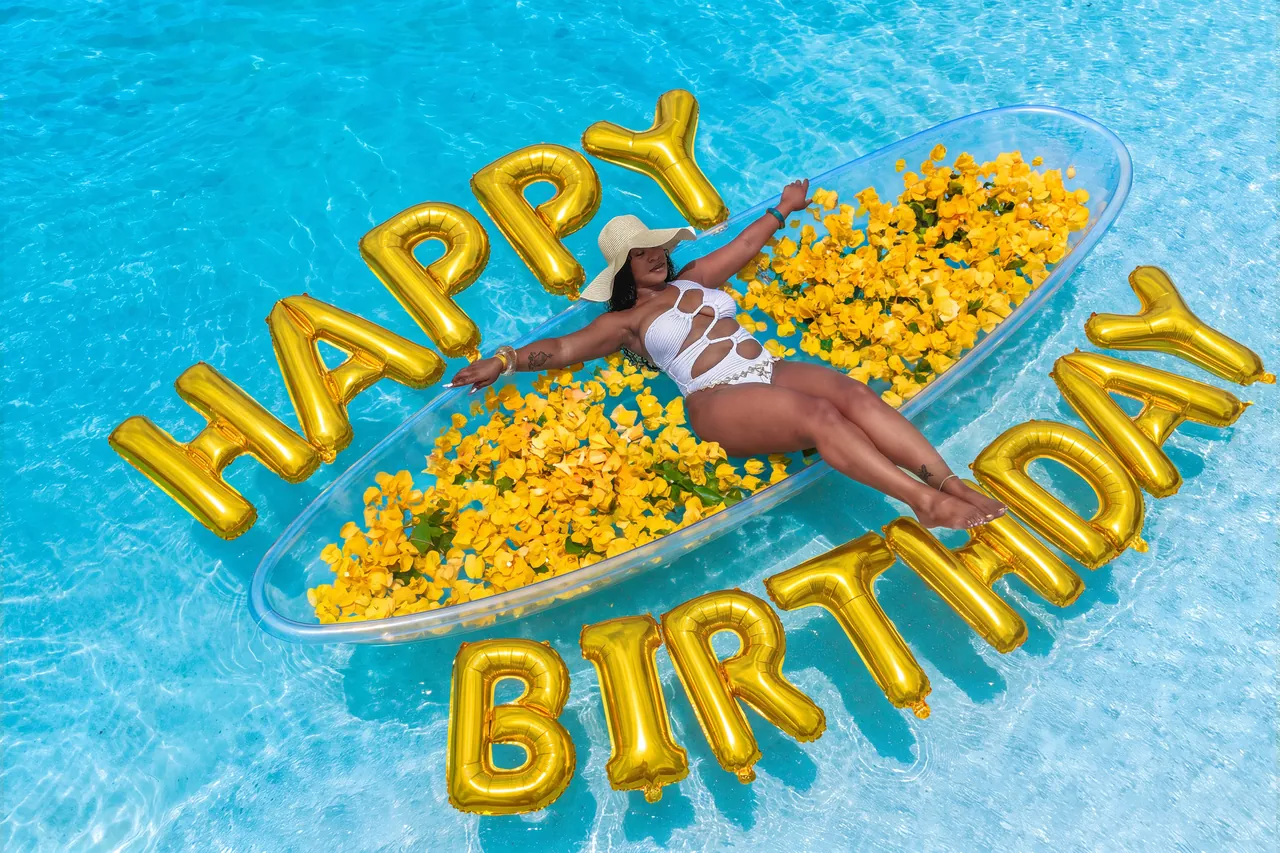 Birthday clear-kayak setup with yellow flowers and gold balloons over clear turquoise water
