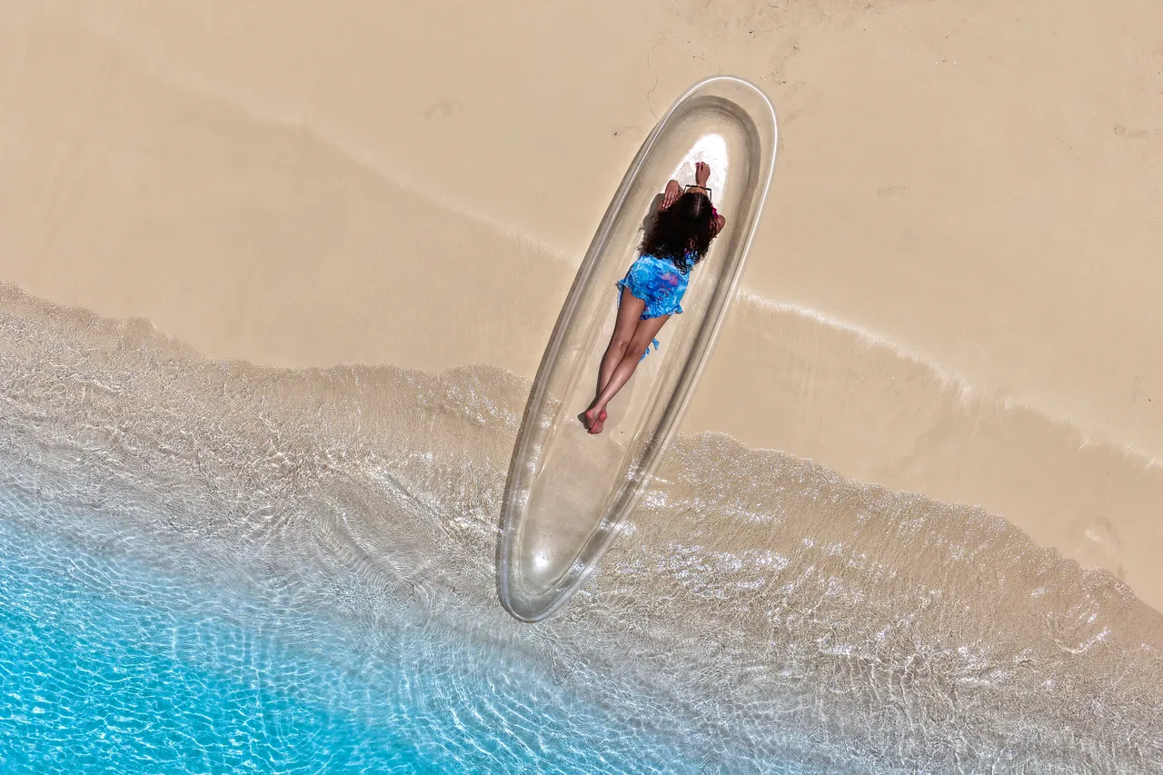 Top-down clear-kayak portrait beside the line where turquoise water meets the beach
