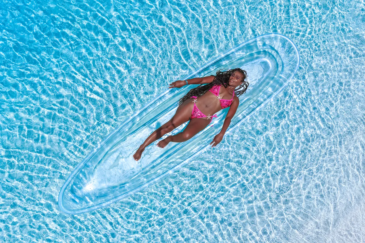 Guest lying inside a clear kayak surrounded by bright water ripples