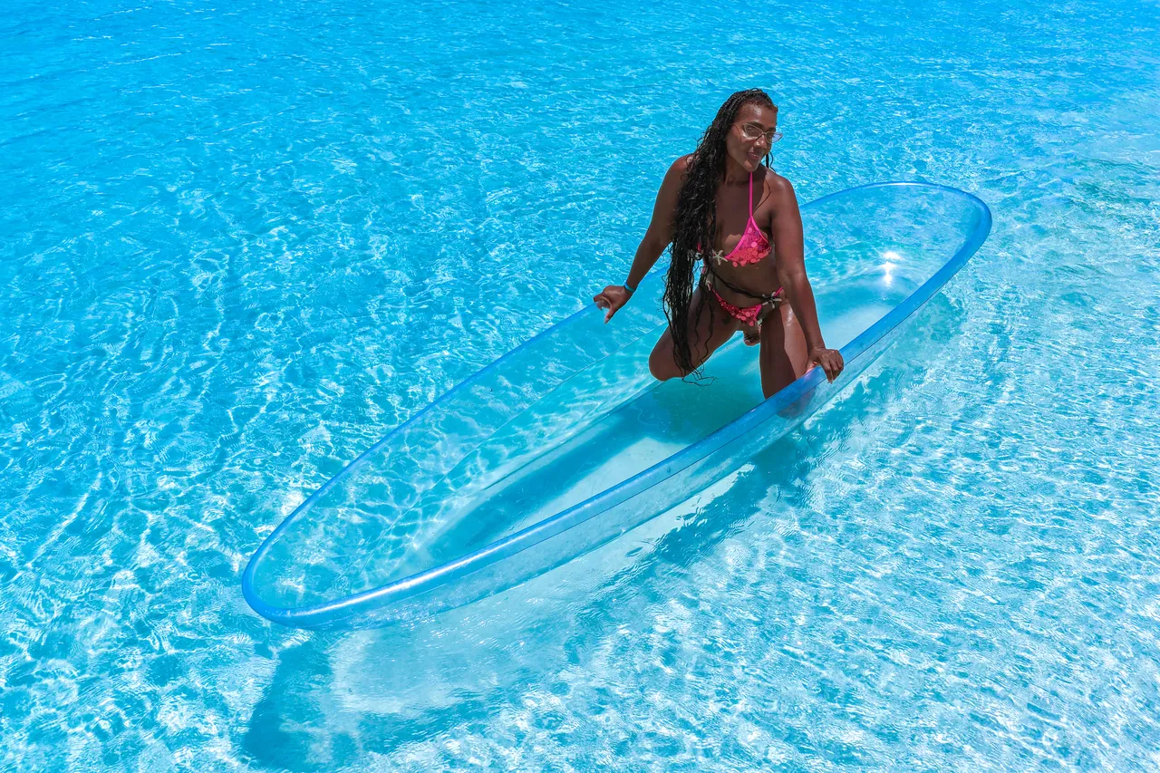 Guest sitting upright in a clear kayak over saturated blue Caribbean water