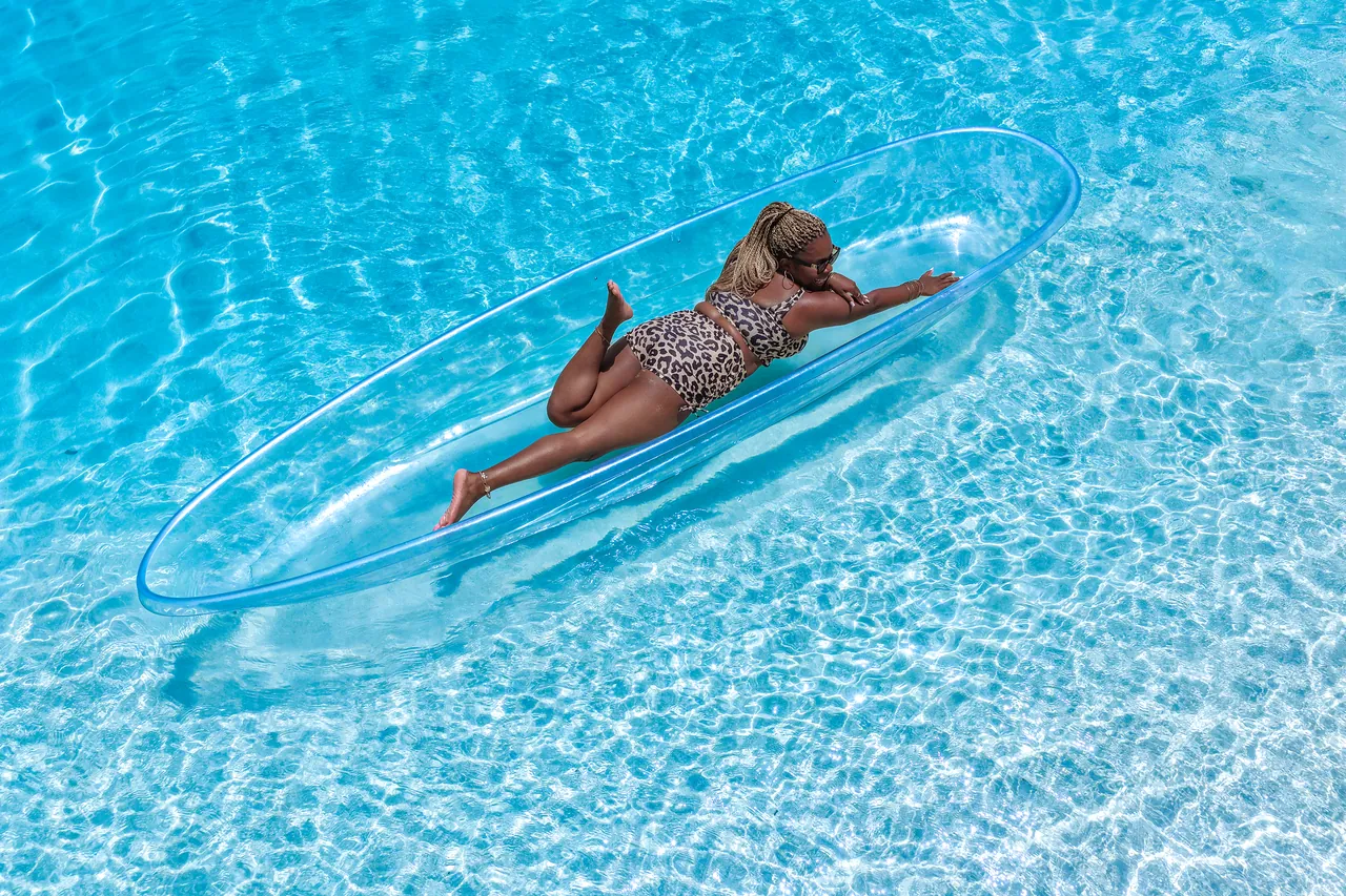 Guest leaning forward in a clear kayak over rippled Caribbean water