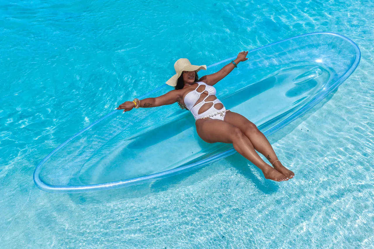 Guest in a white swimsuit and sunhat posing in a clear kayak