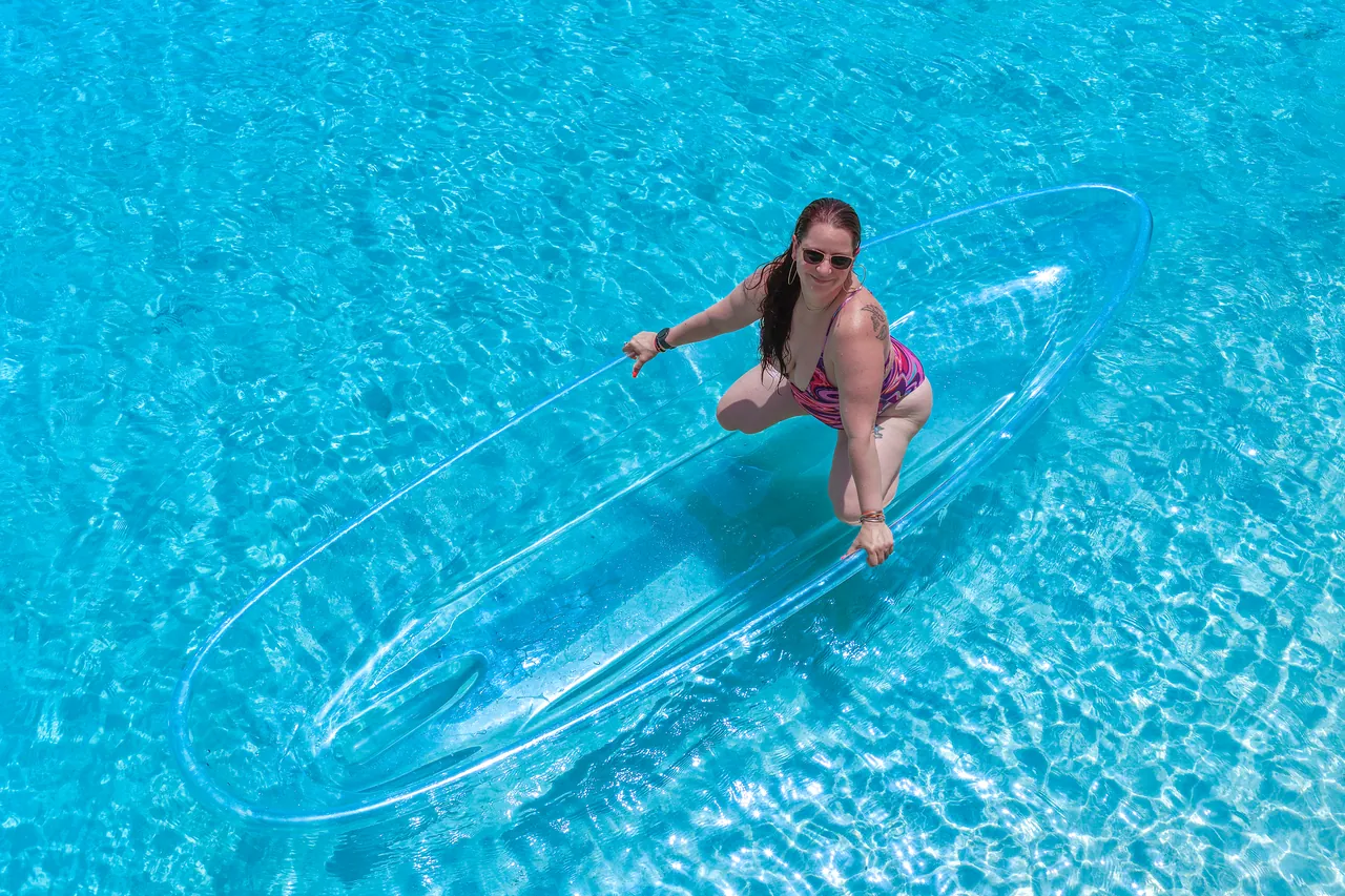 Guest posing in a clear kayak captured from a high aerial angle