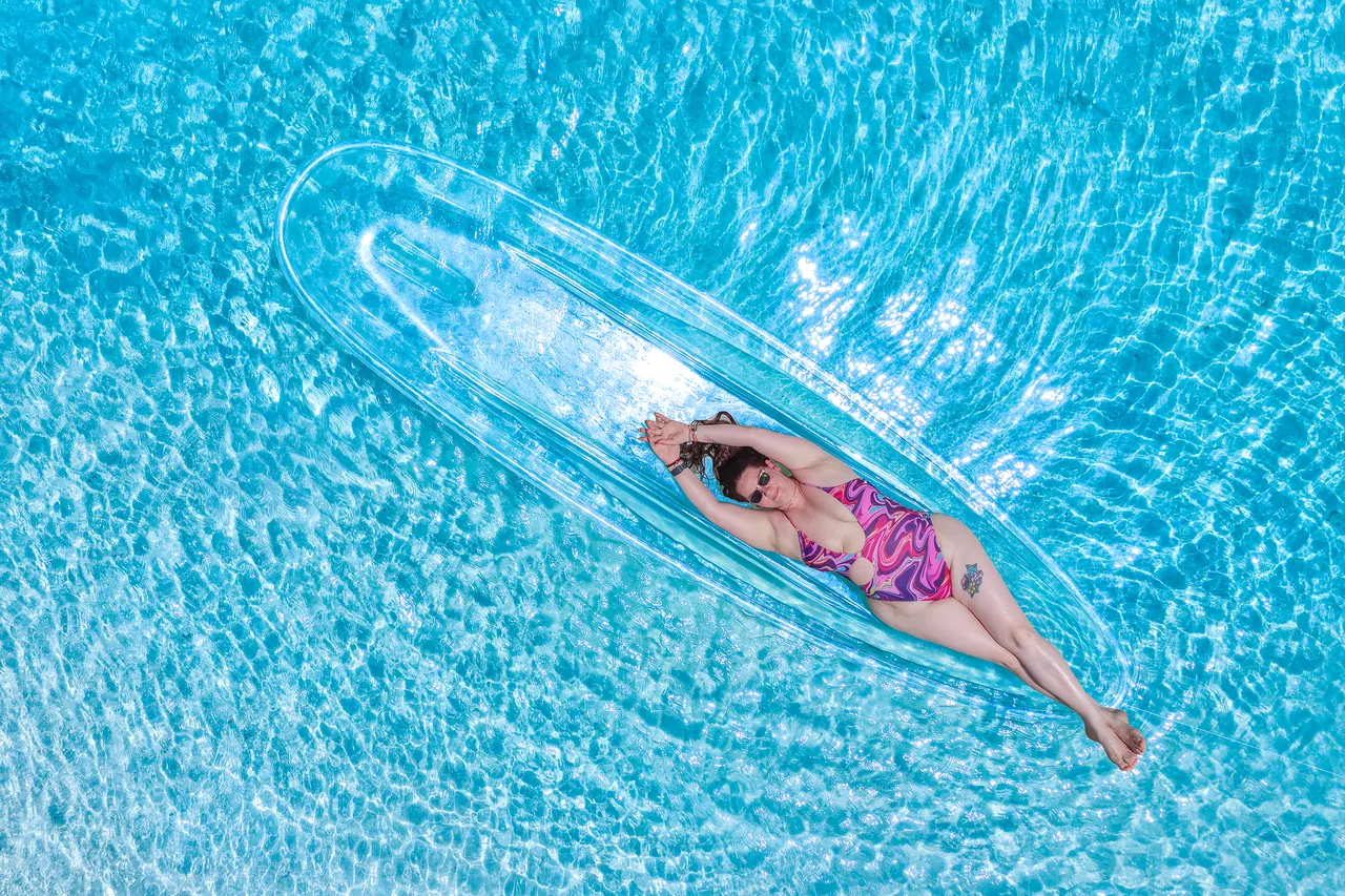 Top-down view of a guest in a clear kayak over deep turquoise water