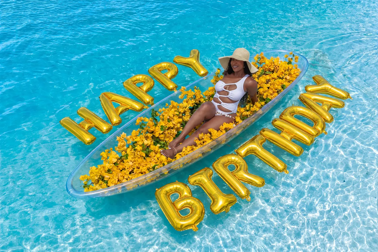 Yellow-flower clear kayak framed by large gold birthday balloons