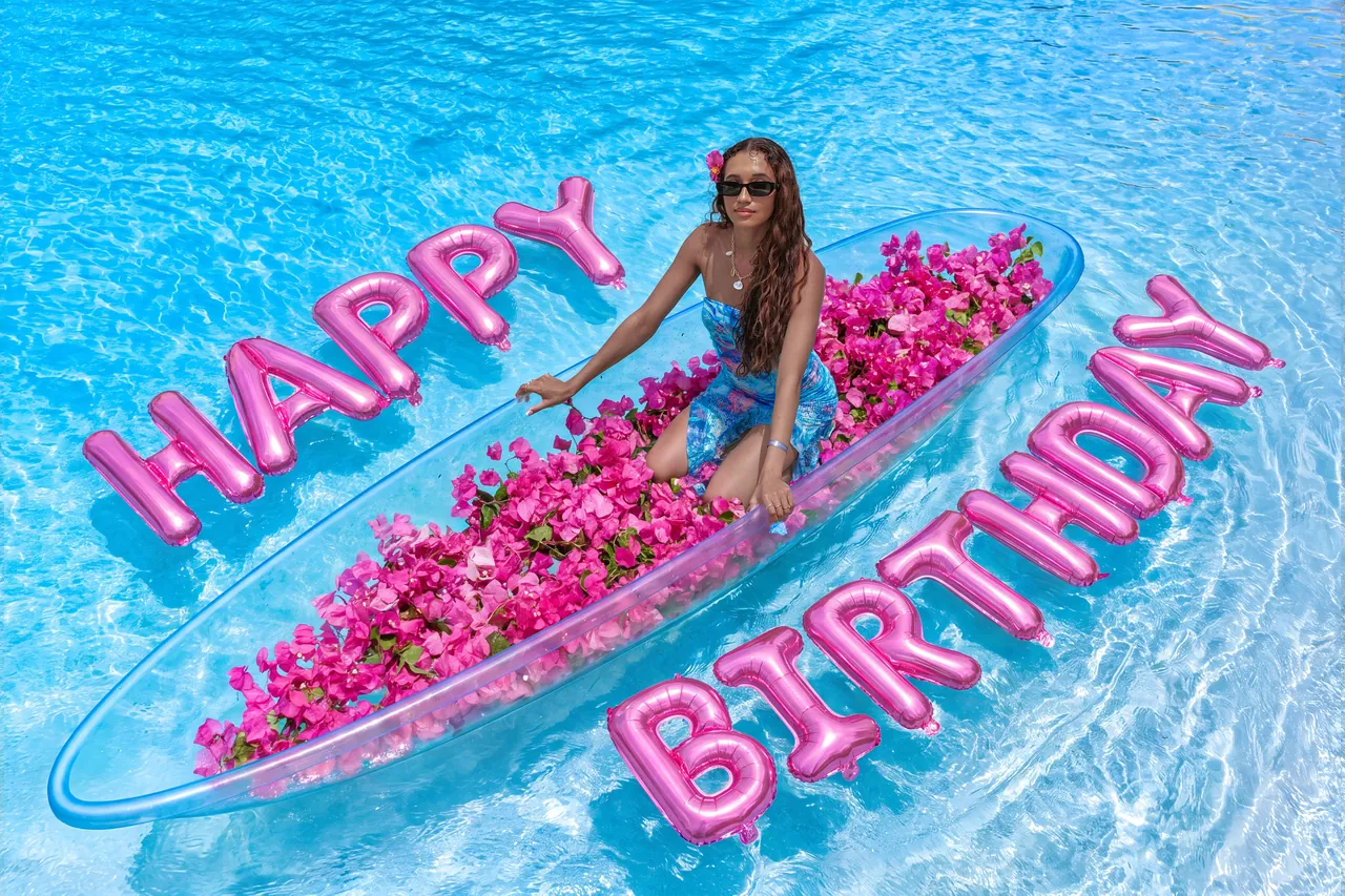 Guest standing in a pink-flower clear kayak framed by pink birthday balloons